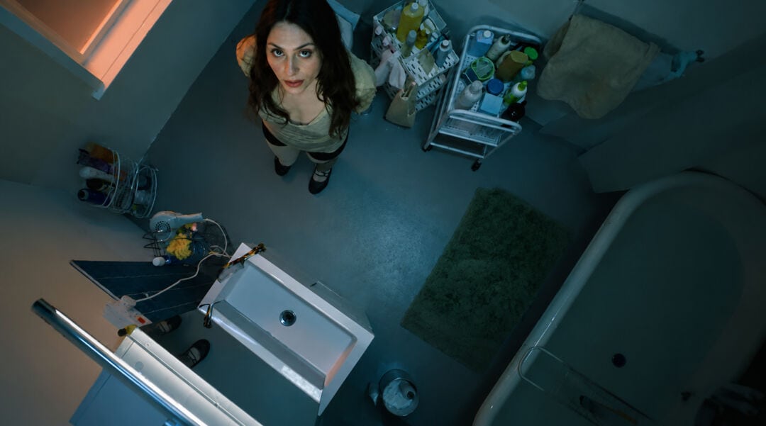 A woman standing in a room with art supplies and equipment, viewed from above.